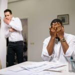 Diverse coworkers in tense office conflict scene, highlighting workplace issues.