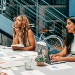 Diverse women engaging in a collaborative meeting at an office desk, focused on planning and innovation.
