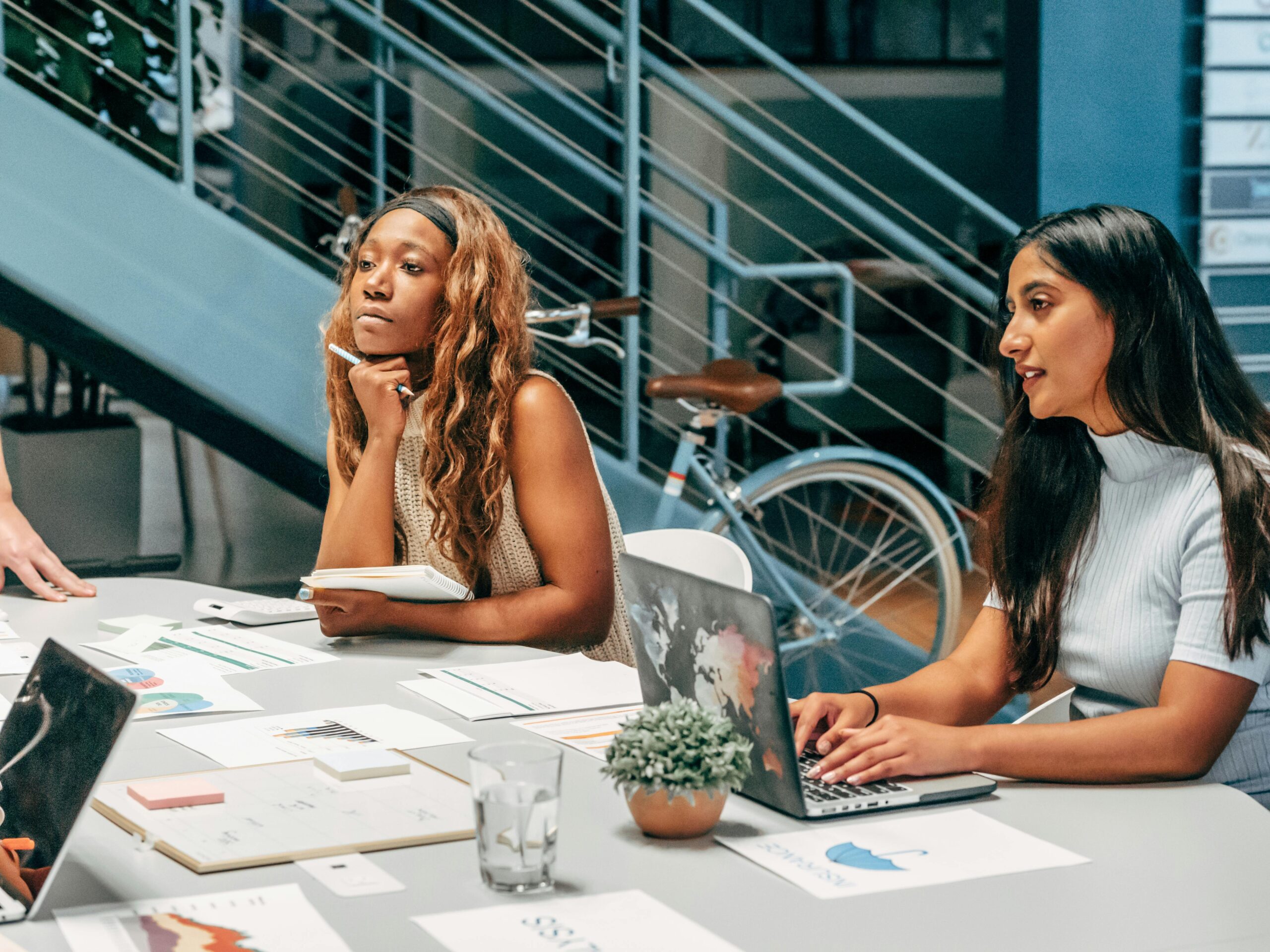Diverse women engaging in a collaborative meeting at an office desk, focused on planning and innovation.